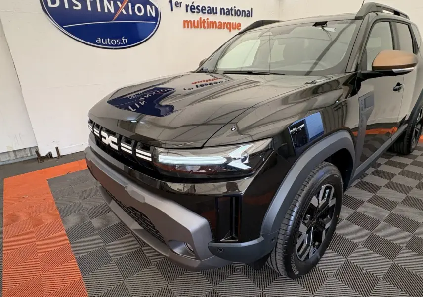 Vue 3/4 avant droit du Dacia Duster 2025 noir avec calandre distinctive et jantes noires en showroom