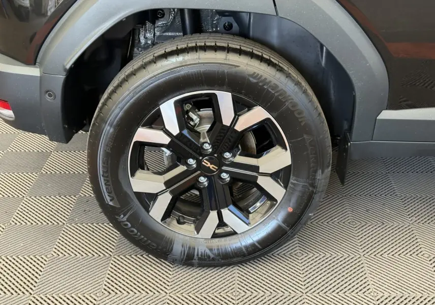 Gros plan sur la roue arrière gauche du Dacia Duster noir 2025, mettant en valeur la jante alliage bicolore moderne.