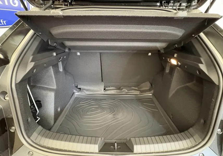 Coffre ouvert noir du Dacia Duster 2025, vue intérieure montrant l'espace de chargement et la moquette protectrice.