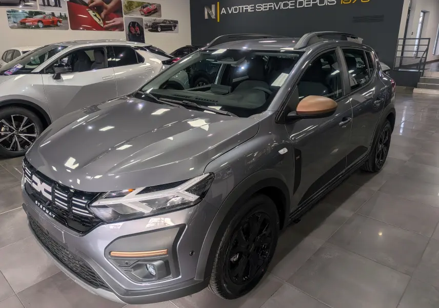 Vue 3/4 avant droite d'une Dacia Sandero Stepway TCe 110 Gris Schiste avec rétroviseurs couleur cuivre et jantes noires.