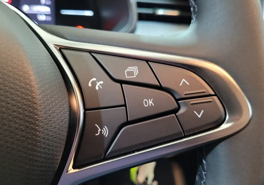 Gros plan sur les commandes multifonctions noires du volant cuir synthétique de la Renault Clio gris foncé Evolution Blue dCi 100 2025.