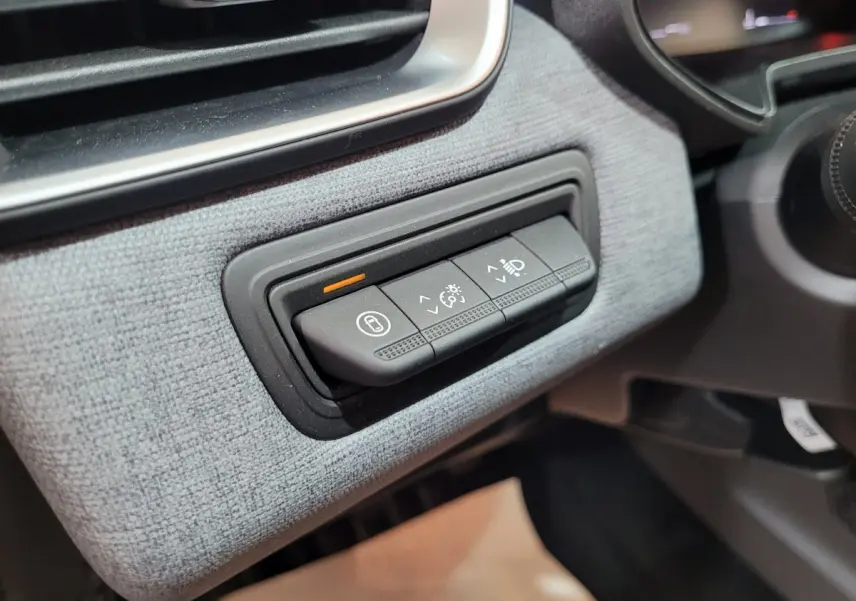 Gros plan sur les commandes d'éclairage et tableau de bord gris clair à texture tissu dans une Renault Clio Evolution Blue dCi 100 2025.