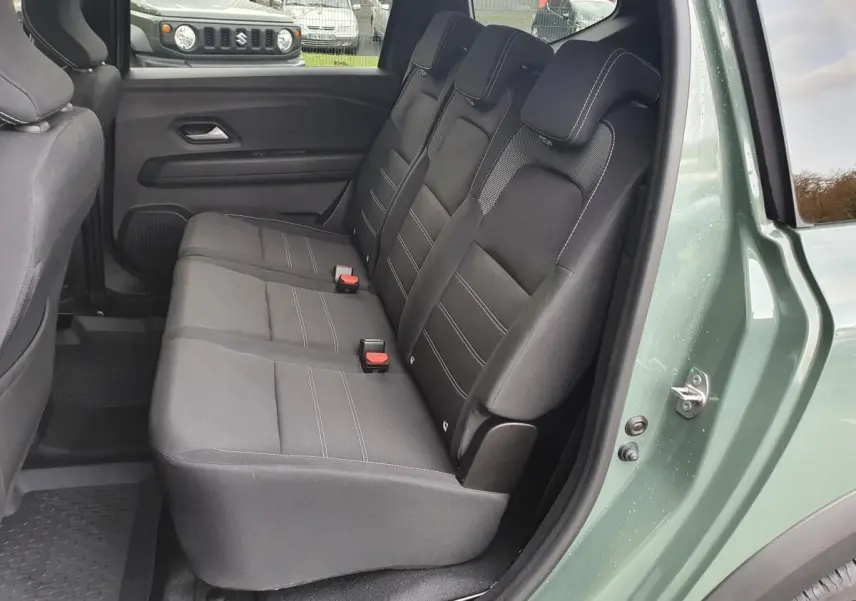 Vue latérale des sièges arrière noirs du Dacia Jogger 2024 en Licken Kaki avec porte arrière ouverte.