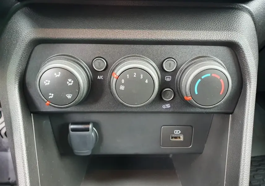 Vue rapprochée des commandes de climatisation manuelle et prise USB du tableau de bord du Dacia Jogger kaki 2024.