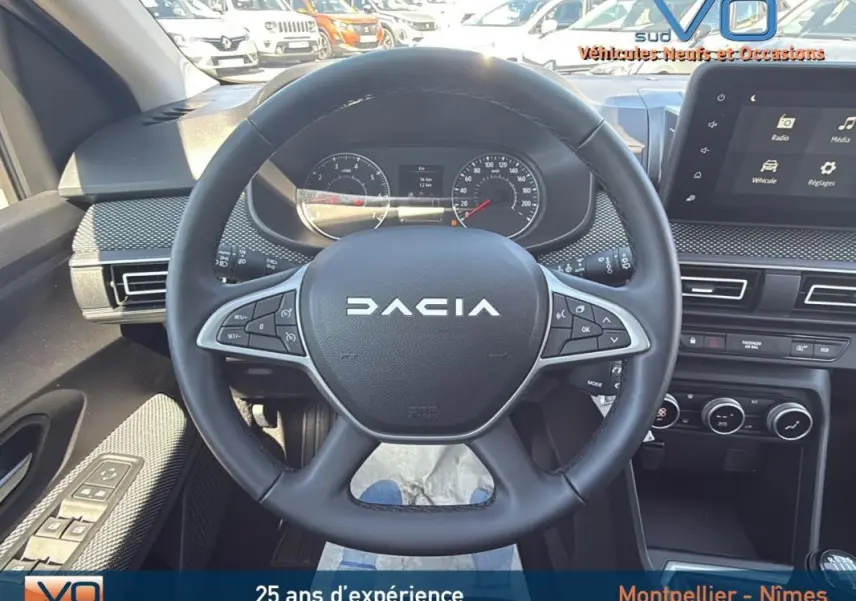 Vue intérieure centrée sur le volant DACIA du JOGGER gris, avec tableau de bord et écran tactile visibles.