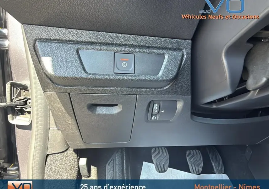 Détail de la partie inférieure gauche du tableau de bord du Dacia Jogger gris 2025, avec commandes et pédales visibles.