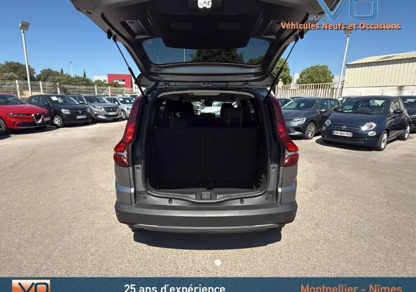 Vue arrière du Dacia Jogger gris 2025 avec coffre ouvert, mettant en valeur l'espace de chargement et les feux arrière.
