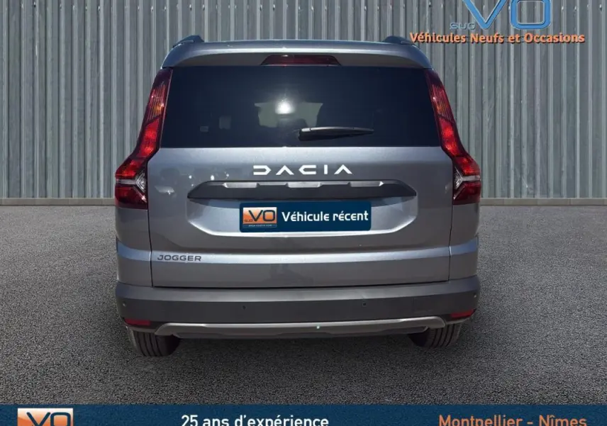 Vue arrière d'un Dacia Jogger gris 2025 avec feux verticaux et hayon fermé sur fond neutre.
