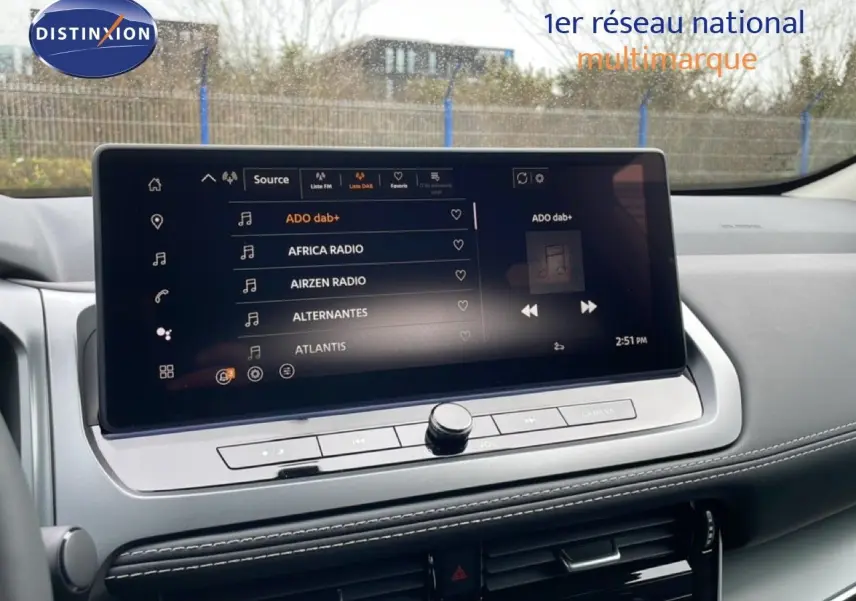 Vue intérieure du tableau de bord du Nissan Qashqai 2025 avec écran tactile multimédia affichant plusieurs stations radio.