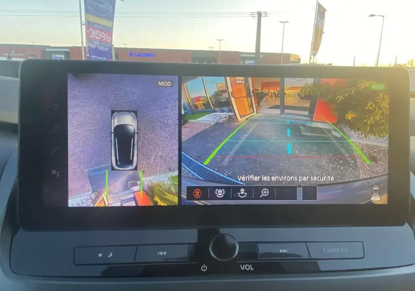 Écran multimédia montrant la caméra de recul et vue 360° du Nissan Qashqai gris ceramic, version 2025, en stationnement.