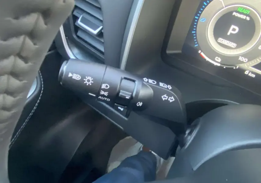 Gros plan sur la commande des feux et clignotants côté gauche du volant dans un Nissan Qashqai gris Ceramic 2025.