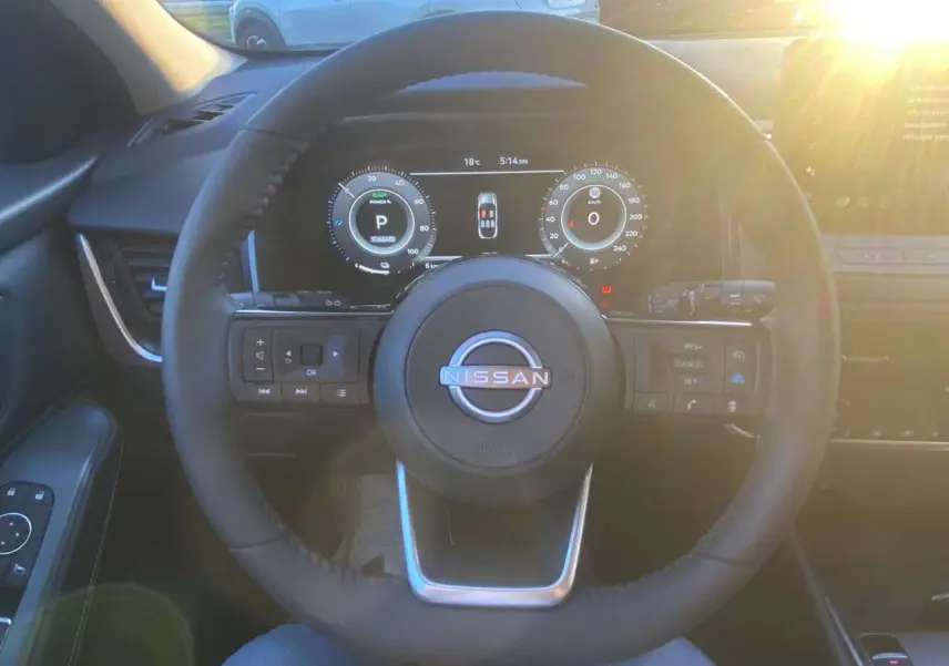Vue intérieure centrée sur le volant du Nissan Qashqai gris Ceramic 2025 avec tableau de bord numérique éclairé.