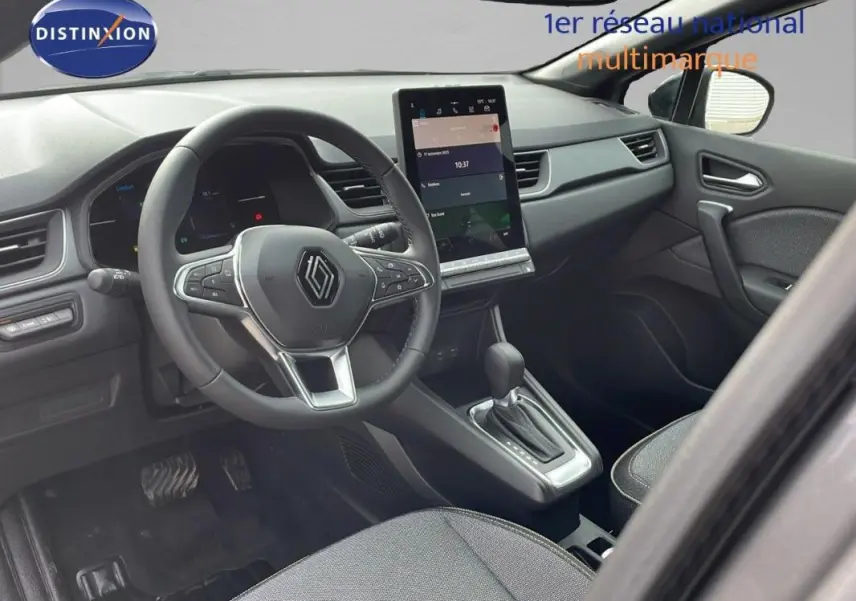 Vue intérieure côté conducteur du Renault Captur gris 2025, volant cuir et écran tactile central visible.