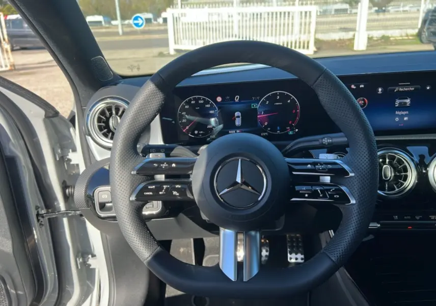 Vue intérieure centrée sur le volant cuir multifonctions de la Mercedes Classe A 200D, avec tableau de bord digital et aérateurs ronds.