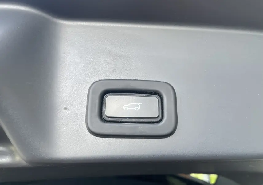 Bouton d'ouverture électrique du hayon sur un Range Rover Evoque P300E PHEV 2022, vue rapprochée intérieure.
