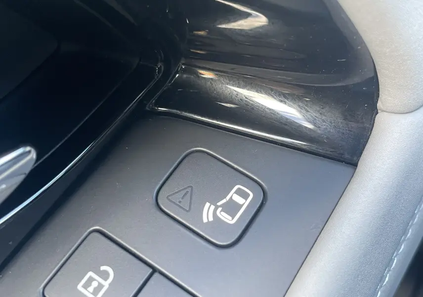 Gros plan sur les boutons de commande intérieurs noirs du Range Rover Evoque 2022, avec symbole d’alerte et déverrouillage.