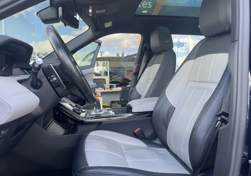Vue intérieure côté conducteur du Range Rover Evoque 2022 en Portofino Blue, sièges cuir bicolores gris et noir.