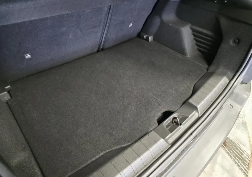 Vue rapprochée du coffre gris du Jeep Avenger 2025, montrant le plancher modulable et la bordure en plastique.