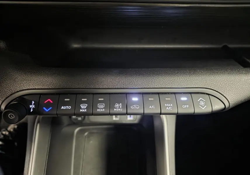 Vue rapprochée de la commande de climatisation noire du Jeep Avenger 2025 avec boutons rétroéclairés blancs et bleus.