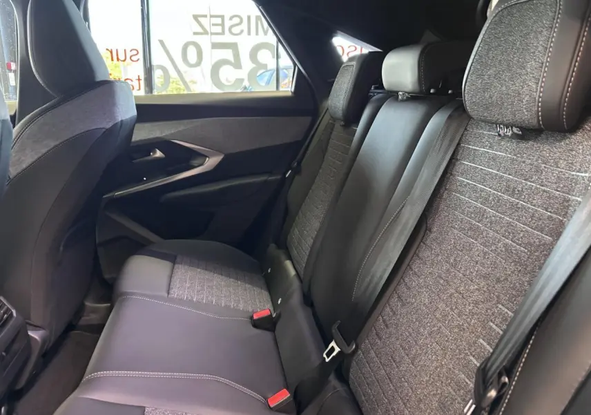Vue intérieure côté droit des sièges arrière gris tissu et noir cuir du Peugeot 3008 hybride 2026 avec ceintures de sécurité visibles.