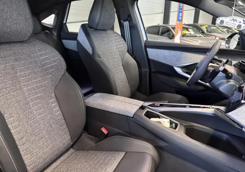 Vue intérieure côté droit du Peugeot 3008 Hybrid 2026, sièges tissu gris et cuir noir avec console centrale assortie.