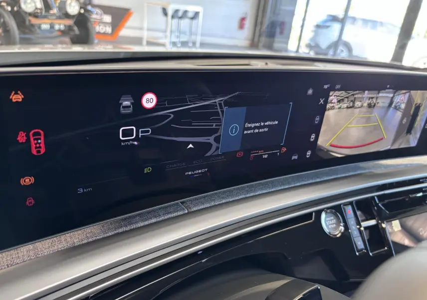 Vue rapprochée de l'écran numérique du tableau de bord du Peugeot 3008 hybride blanc, affichant la caméra de recul et les alertes.