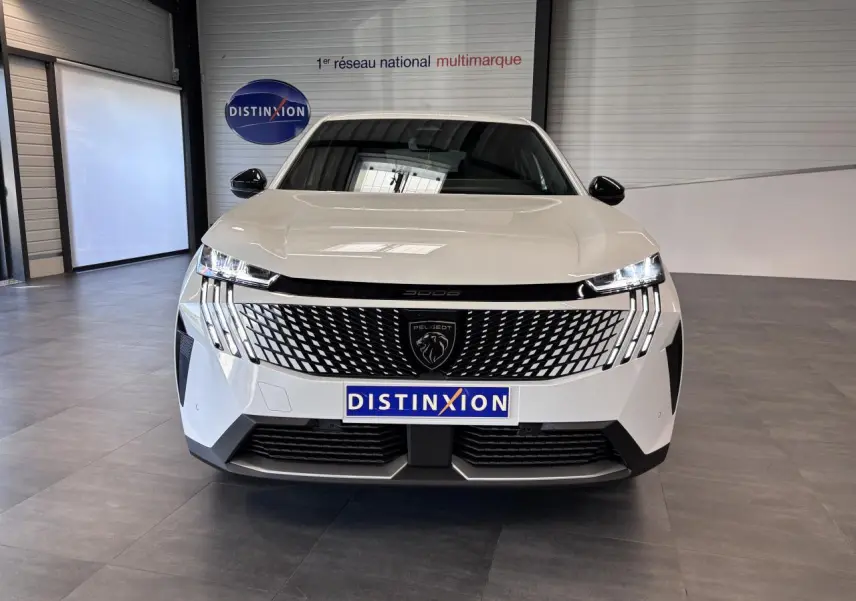 Vue avant d’un Peugeot 3008 blanc avec calandre noire laquée et feux LED 3 griffes, en intérieur showroom.
