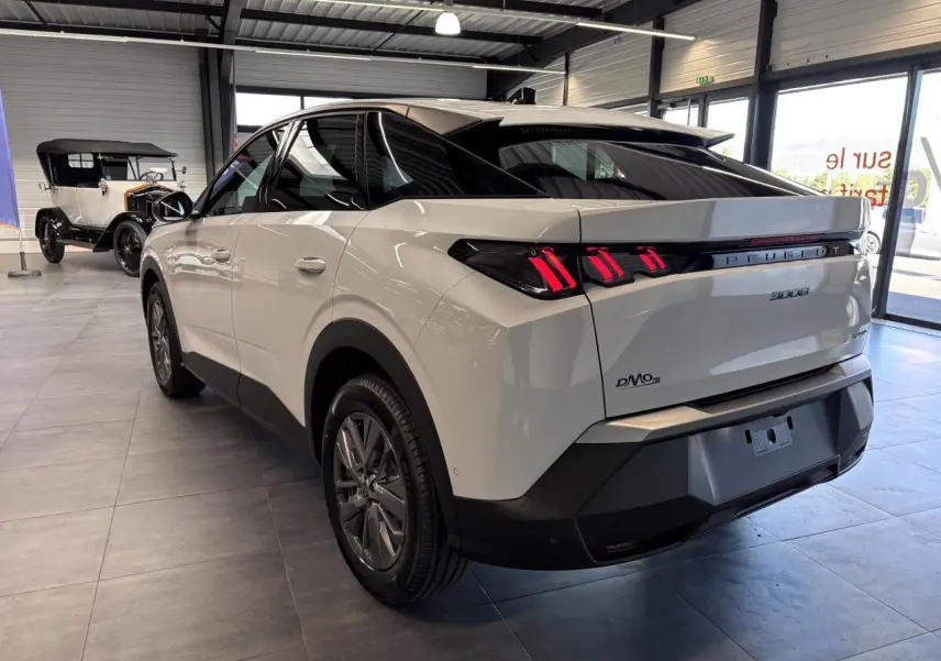 Vue 3/4 arrière droite du Peugeot 3008 blanc hybride avec feux arrière LED à 3 griffes et bandeau noir laqué.