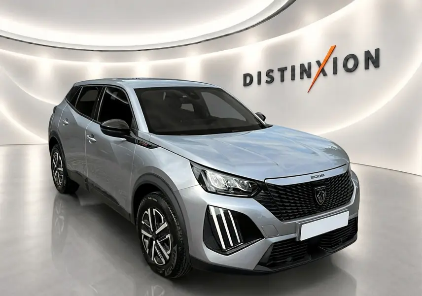Peugeot 2008 gris en 3/4 avant droit, avec calandre noire et feux LED distinctifs, sur fond blanc lumineux.