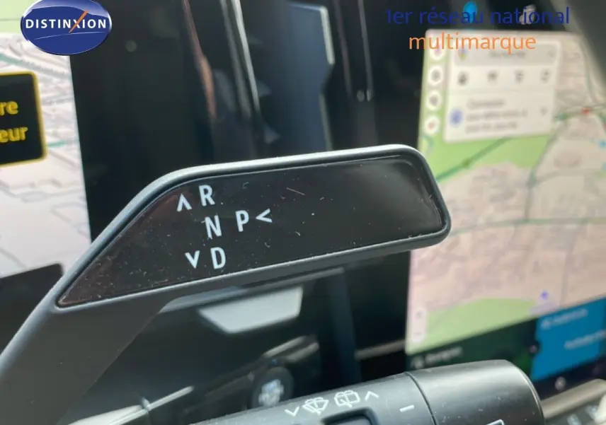 Gros plan sur le levier de vitesses automatique du Renault Espace VI hybride, avec écran tactile de navigation en arrière-plan.