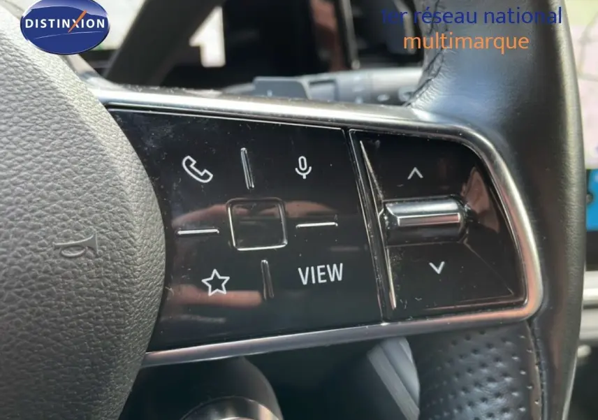 Gros plan sur les commandes gauche du volant en cuir noir du Renault Espace VI gris schiste, avec boutons multifonctions et molette.