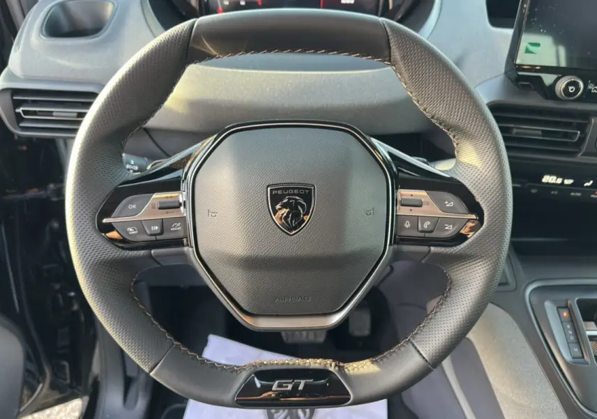 Vue rapprochée du volant cuir multifonctions noir avec logo Peugeot et badge GT du Rifter 2025.