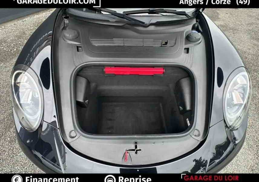 Vue plongeante sur le coffre avant ouvert d'une Porsche 911 Carrera GTS Coupé noire, avec feux ronds visibles.