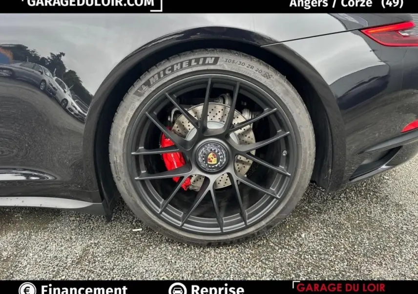 Gros plan sur la roue arrière droite noire d'une Porsche 911 Carrera GTS Coupé 2018 avec étrier de frein rouge visible.