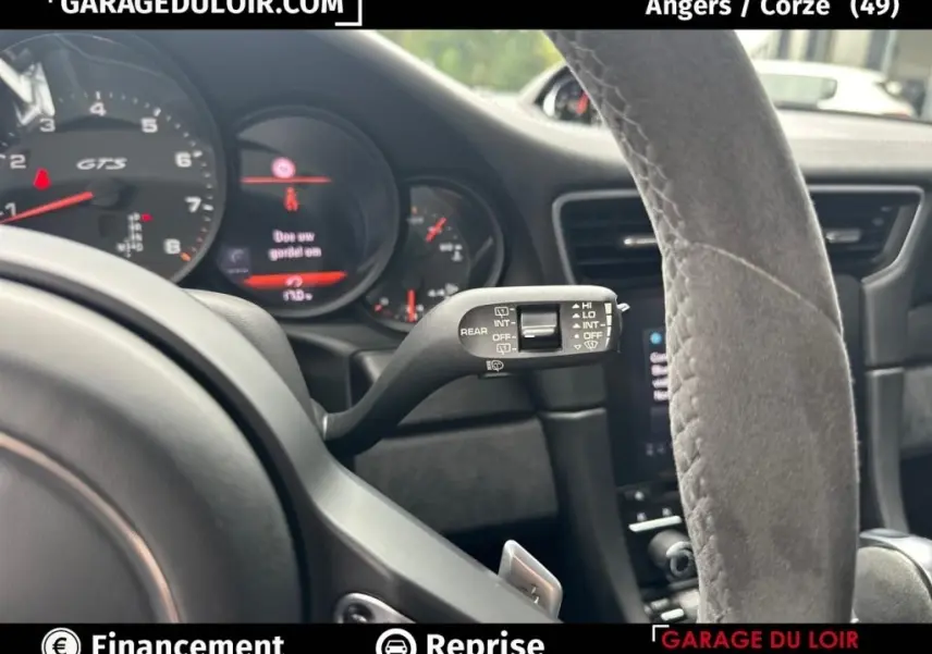 Gros plan sur le tableau de bord et le volant en alcantara gris d’une Porsche 911 Carrera GTS Coupé 2018, intérieur noir.
