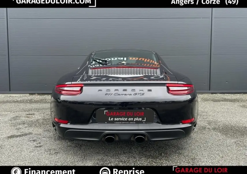 Vue arrière d'une Porsche 911 Carrera GTS Coupé noire, avec double sortie d'échappement centrale et feux arrière LED.