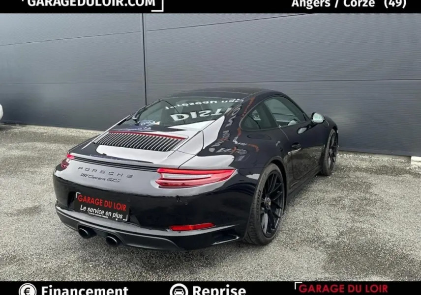 Vue 3/4 arrière droite d'une Porsche 911 Carrera GTS Coupé noire brillante avec jantes noires et feux arrière LED.
