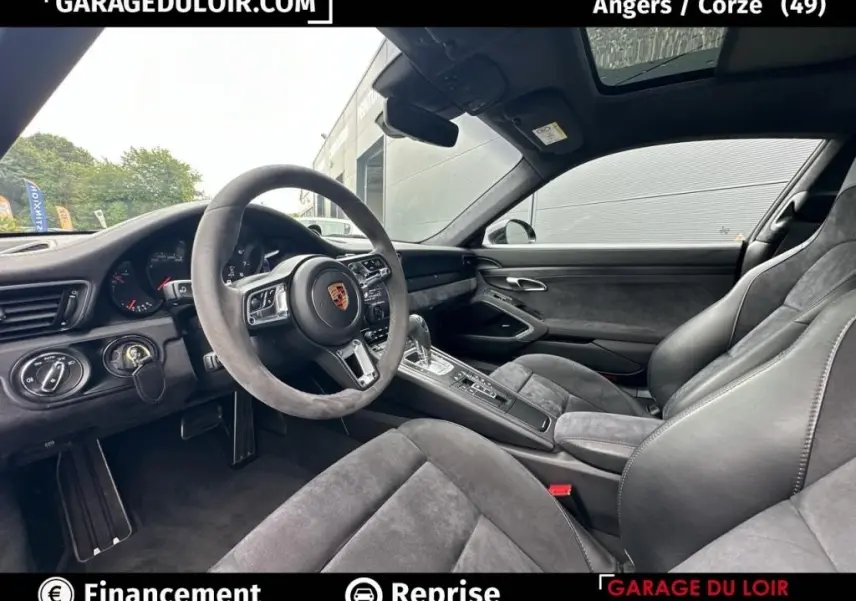 Vue intérieure côté conducteur de la Porsche 911 Carrera GTS Coupé 2018 avec sellerie alcantara grise et volant sport.