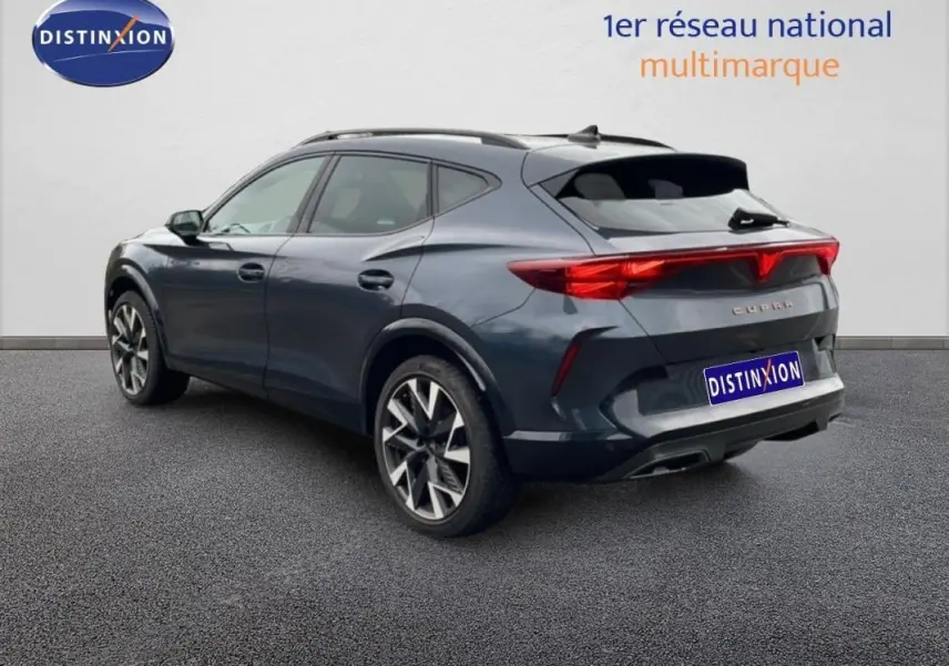 Vue 3/4 arrière droite d’un CUPRA Formentor gris avec barres de toit et jantes aluminium distinctives.