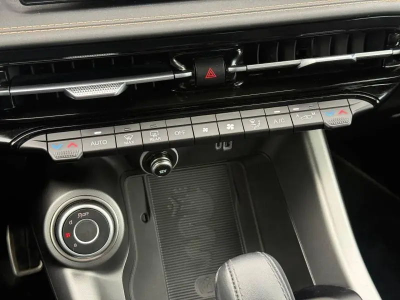 Détail de la console centrale de l'Alfa Romeo Tonale 2025 gris Vesuvio, avec commandes climatisation et bouton de sélection de mode.