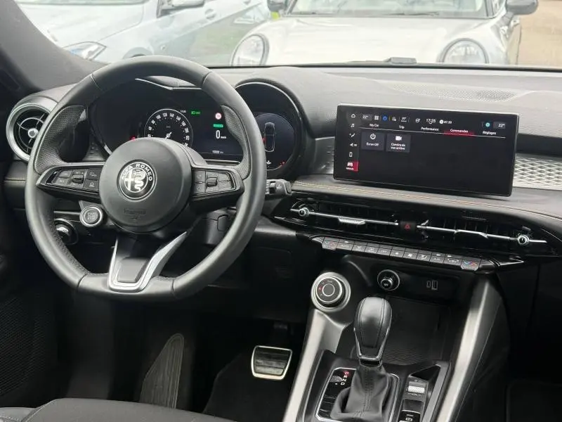 Intérieur de l'Alfa Romeo Tonale 1.5 Hybrid 130ch Sprint 2025, vue du poste de conduite avec volant cuir et écran tactile.