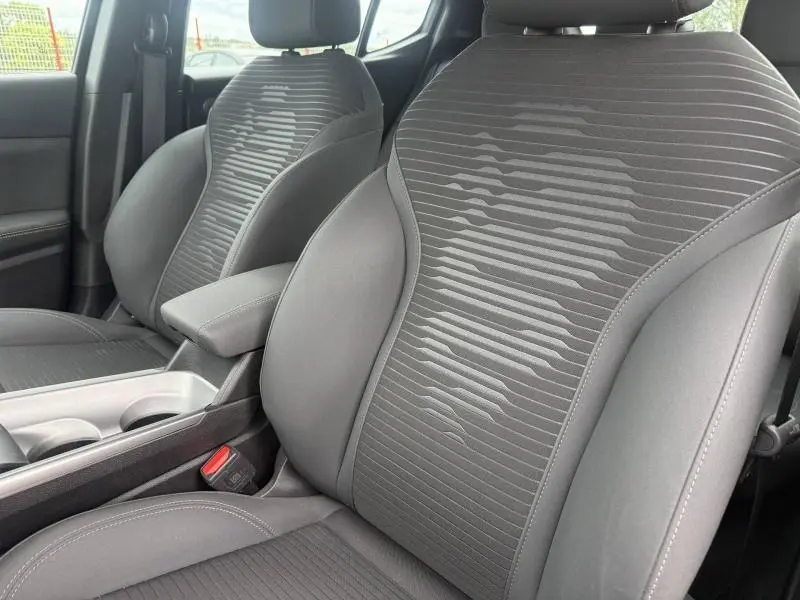 Vue rapprochée des sièges avant gris foncé de l'Alfa Romeo Tonale 2025 avec accoudoir central et détails en tissu texturé.