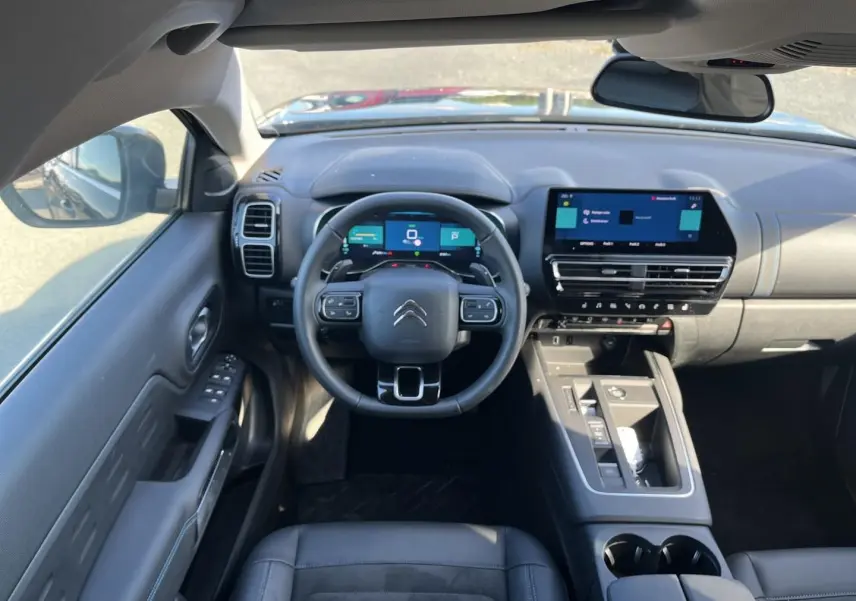 Vue intérieure avant du Citroën C5 Aircross hybride 2024 noir, avec tableau de bord numérique et écran tactile central.