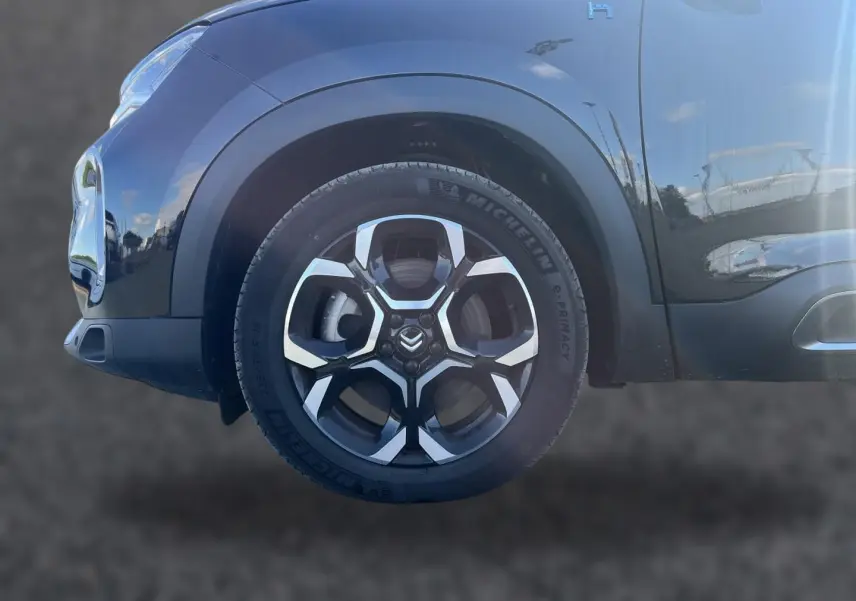 Gros plan sur la roue avant gauche noire du Citroën C5 Aircross 2024 avec jante alu et logo Citroën visible.