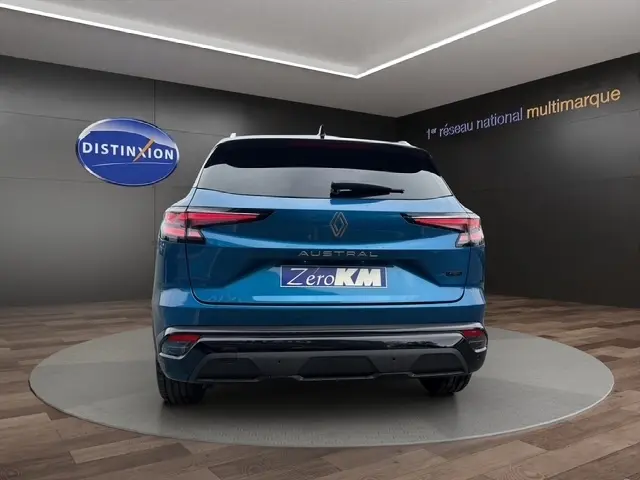 Vue arrière d'un Renault Austral bleu bi-ton avec hayon motorisé et logo RS dans un showroom.