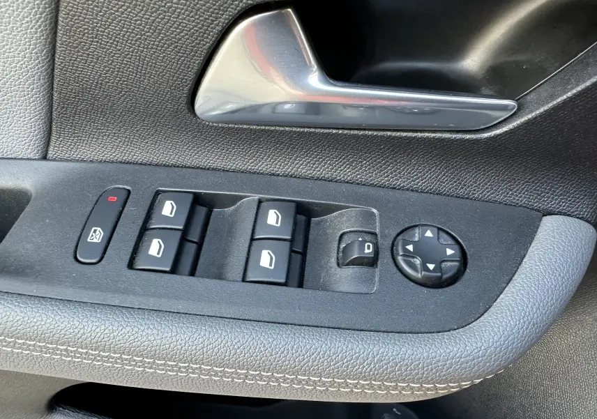 Gros plan sur la commande des vitres et rétroviseurs côté conducteur de l'Opel Mokka Elegance 2021, intérieur noir.