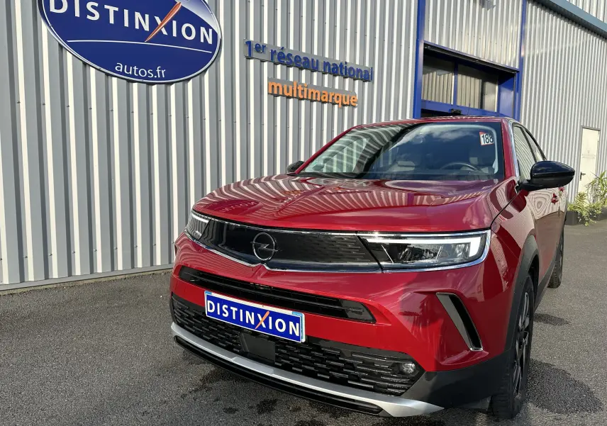 Opel Mokka Elegance rouge Kardinal en 3/4 avant droit, avec calandre noire et phares LED fins visibles.