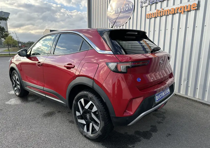 Vue 3/4 arrière droite d'un Opel Mokka rouge Kardinal 2021 avec jantes noires et toit noir brillant.
