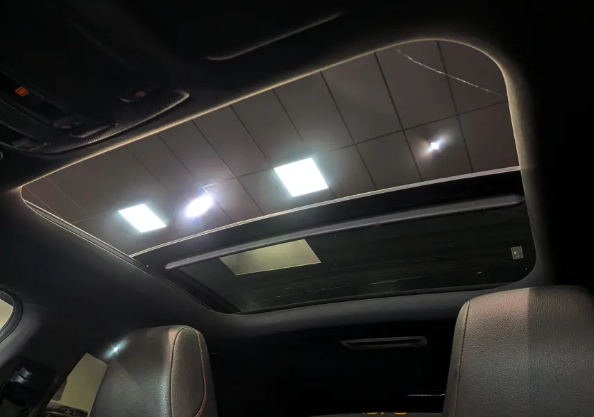 Toit ouvrant panoramique vu de l'intérieur sur les sièges en cuir noir d'une Mercedes Classe CLA 200 Fascination 2017.