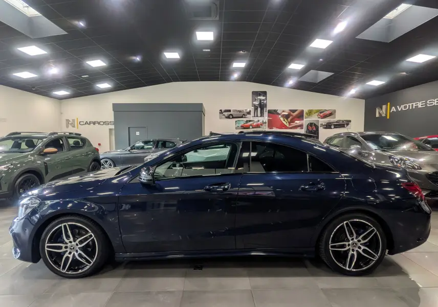 Profil côté gauche d'une Mercedes Classe CLA 200 Fascination bleu Cavansite avec jantes AMG en showroom.